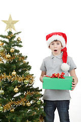 Image showing happy boy in santa hat surprised by christmas present