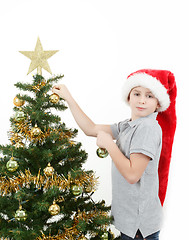 Image showing Boy with santa hat decorates the Christmas tree