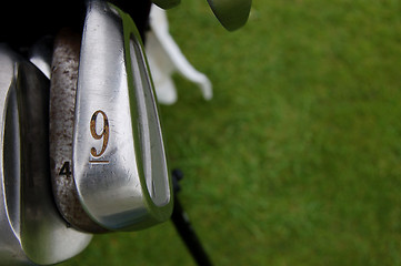 Image showing Nine iron and golf clubs on the green