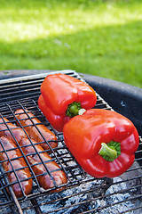 Image showing Red sweet pepper and sausages on a grill