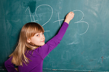 Image showing Young girl writing numbers on chalkboard