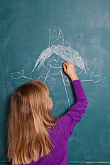 Image showing Young girl drawing on chalkboard