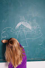 Image showing Young girl drawing on chalkboard