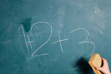 Image showing Hand holding sponge over chalkboard 