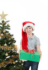 Image showing happy boy in santa hat surprised by christmas present