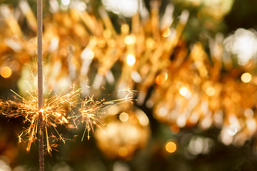 Image showing burning sparkler and out of focus christmas tree 