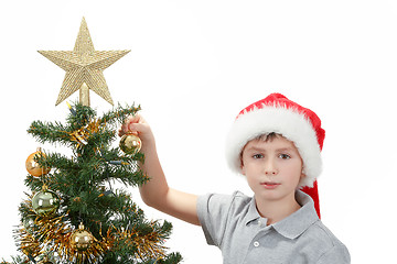 Image showing Boy with santa hat decorates the Christmas tree