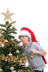 Image showing Boy with santa hat sticking out tongue at  the Christmas tree