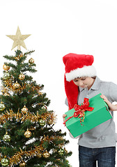 Image showing happy boy in santa hat surprised by christmas present