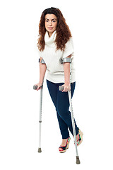 Image showing Sad faced woman limping with crutches