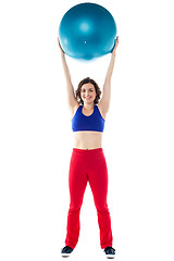 Image showing Happy woman lifting pilates ball upwards