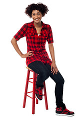 Image showing Casual young woman sitting on stool