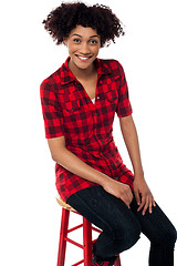 Image showing Curly haired fashion model sitting on red stool