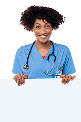 Image showing Joyous female doctor standing behind ad board