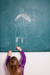 Image showing Young girl drawing on chalkboard