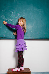 Image showing Young girl drawing on chalkboard