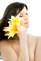 Image showing brunette with yellow lily flowers in spa