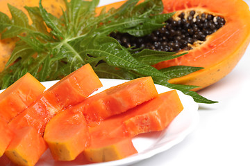 Image showing Ripe papaya and slices with seeds and green leaf isolated on a w