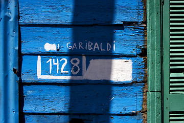 Image showing green wood venetian blind and a blue garibaldi wall