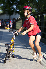 Image showing Very young triathlete pushing his bike.