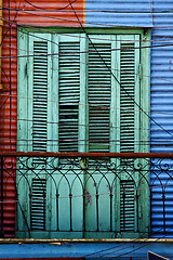 Image showing green wood venetian blind and a red blue wall 