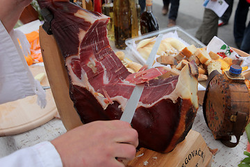 Image showing A hand cutting prosciutto