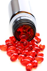 Image showing Red capsules with vitamins spilled from the bottle.