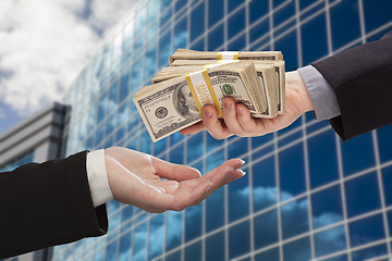 Image showing Male Handing Stack of Cash to Woman with Corporate Building