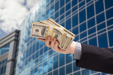 Image showing Male Hand Holding Stack of Cash with Corporate Building