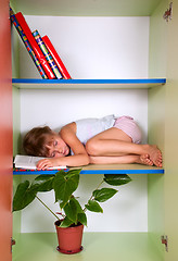 Image showing tired kid sleeping on the shelf with a book instead of a pillow