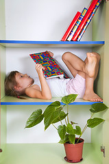 Image showing child reading a book in a bookcase