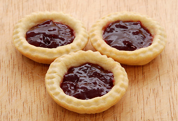 Image showing Three tasty jam tarts on a wooden table