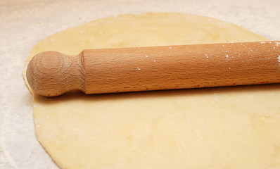 Image showing Fresh pastry rolled out with a wooden rolling pin