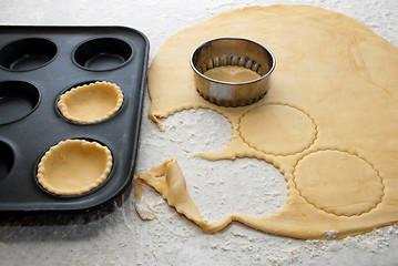 Image showing Pastry circles being cut and filling a bun tin to make jam tarts