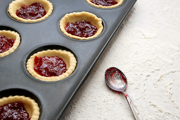 Image showing Filled, uncooked jam tarts in a tin