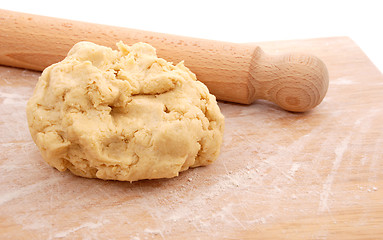 Image showing Wooden rolling pin and a fresh ball of pastry on a floured board