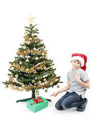 Image showing happy boy in santa hat surprised by christmas present