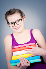 Image showing Silly smiling schoolgirl with glasses and lots of books