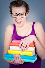 Image showing Silly smiling schoolgirl with glasses and lots of books