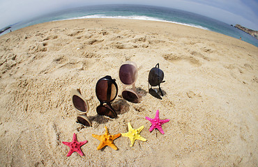 Image showing Four pairs of sunglasses on the beach 