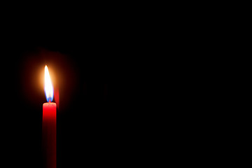 Image showing burning red candle with black background