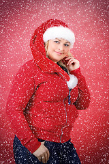 Image showing Joyful pretty woman in red santa claus hat smiling with snowflakes