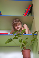 Image showing 	playful little girl hiding on the shelf