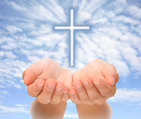 Image showing Hands holding Christian cross with light beams