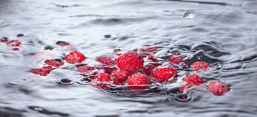 Image showing Red Raspberries Dropped into Water with Splash
