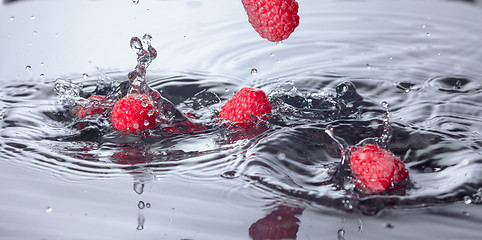 Image showing Red Raspberries Dropped into Water with Splash