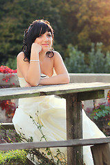 Image showing Girl in the wedding dress sitting on the bench