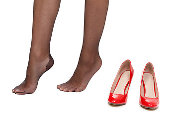 Image showing Tired female legs on a white background next to the red shoes