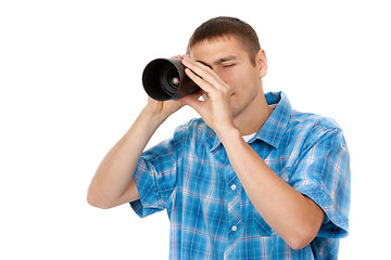 Image showing Handsome young man holding camera lens like it was spyglass on w