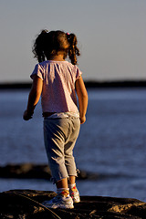 Image showing little girl on the rock in the sunrise 